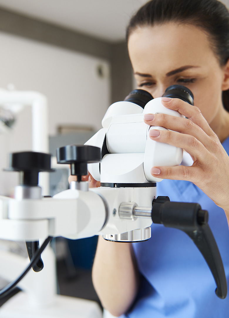 Close up of female dentist looking through dental microscope
